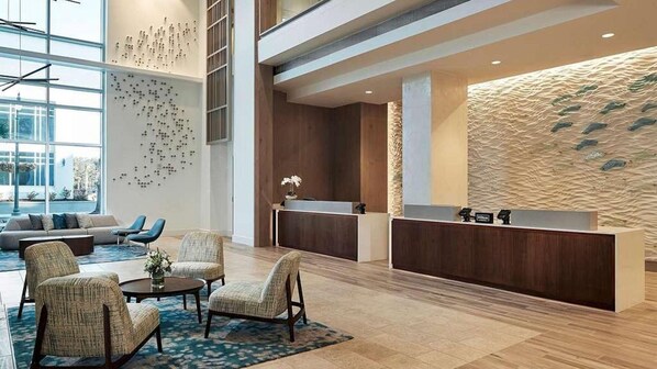 A modern lobby with a reception desk, seating area, and a decorative wall.