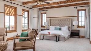 Una camera da letto con un letto grande, una sedia di legno, un comodino e una finestra con tende.