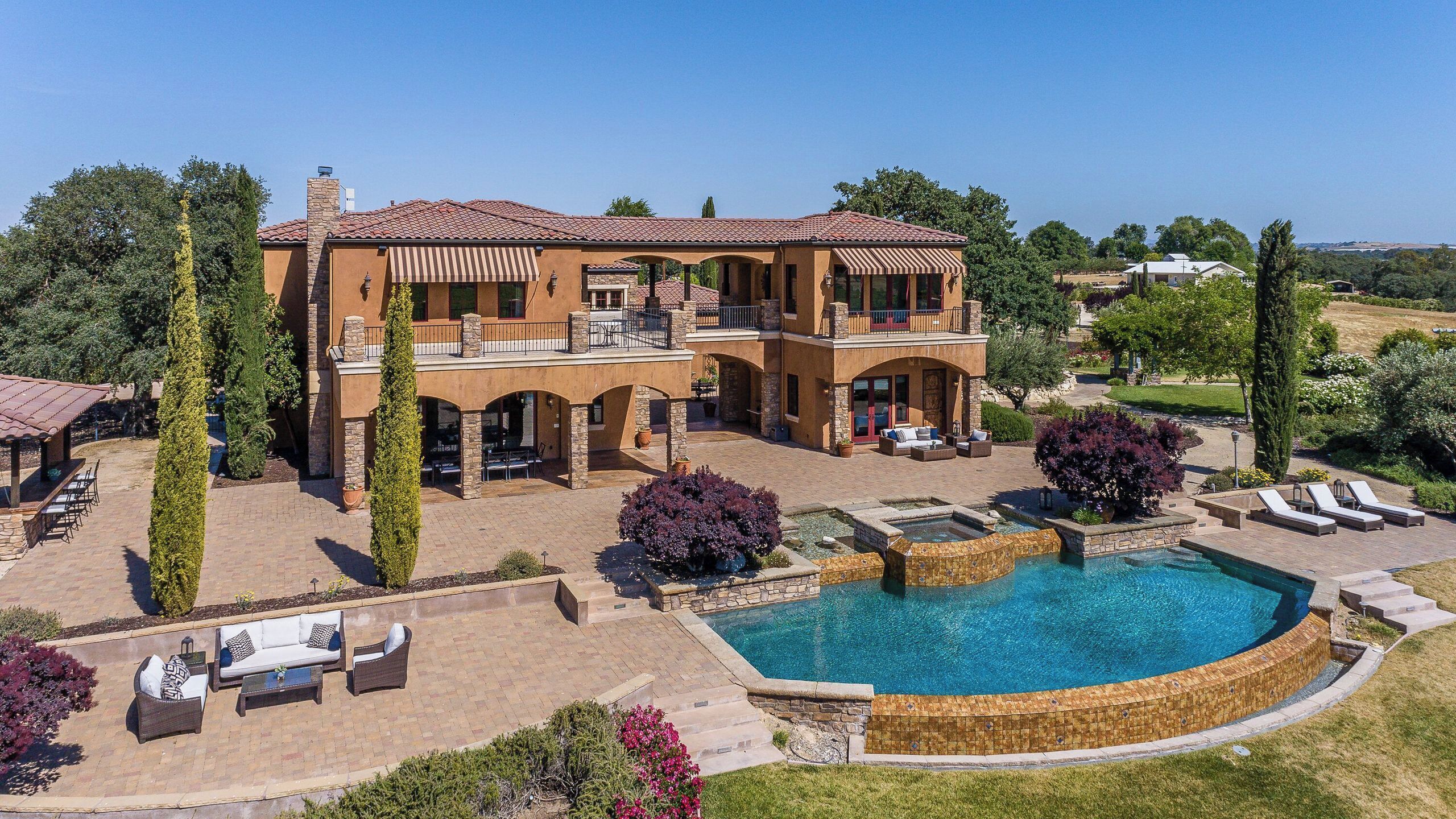 Une grande maison à deux étages avec une piscine et un espace extérieur aménagé pour se détendre.