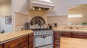 A kitchen with a gas stove, wooden cabinets, and a decorative backsplash. - Mira Vista Vineyard Estate by Avantstay Infinity Pool 82-acre Estate (Paso Robles)