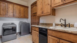 A kitchen with wooden cabinets, a built-in dishwasher, a stove, and a sink with a vintage faucet. - Mira Vista Vineyard Estate by Avantstay Infinity Pool 82-acre Estate (Paso Robles)