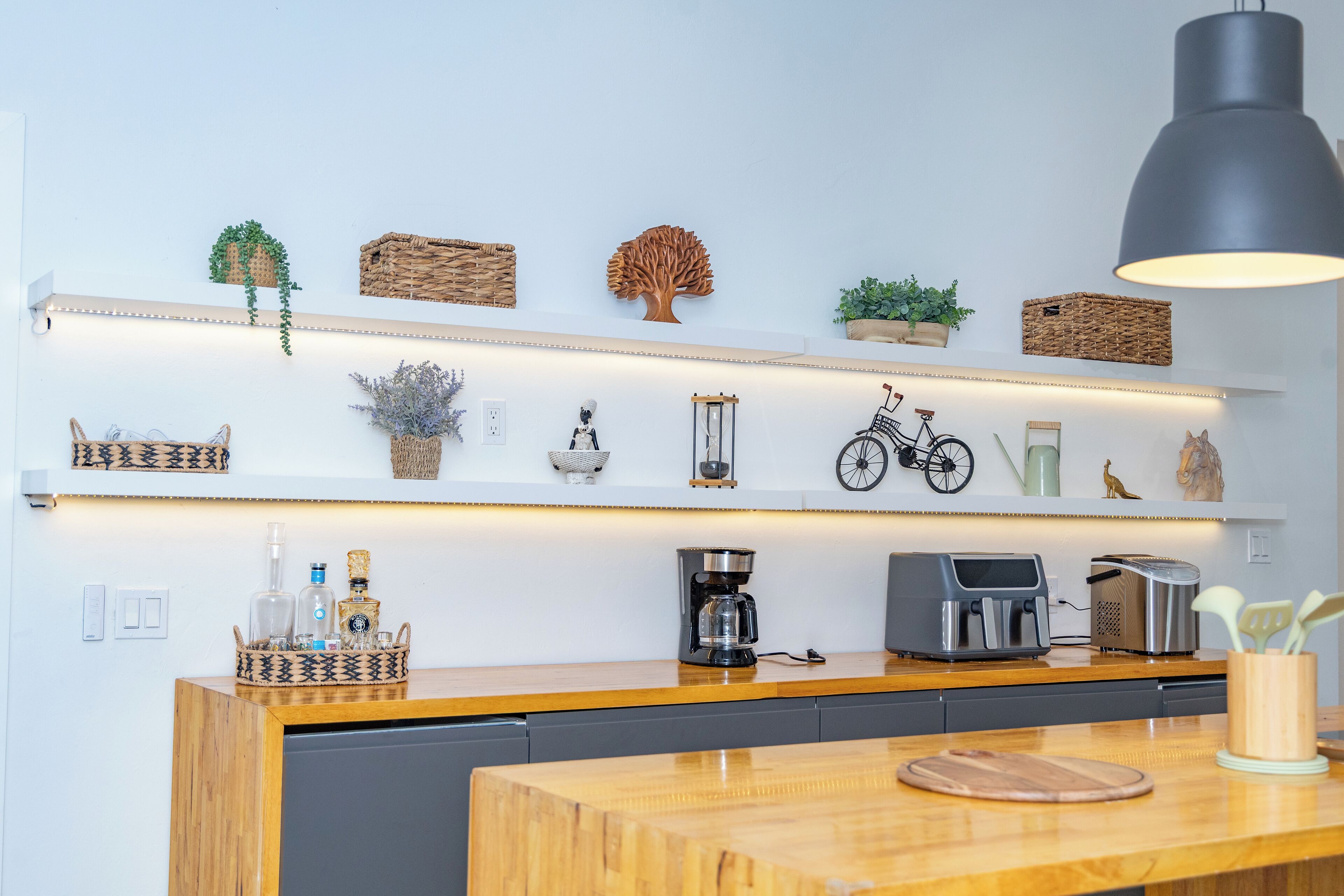 A kitchen with a wooden countertop, a coffee maker, a toaster, and shelves with decorative items.