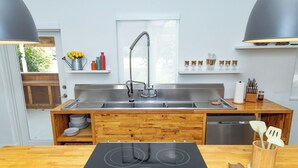 A modern kitchen with a double sink, wooden cabinetry, and a built-in dishwasher.