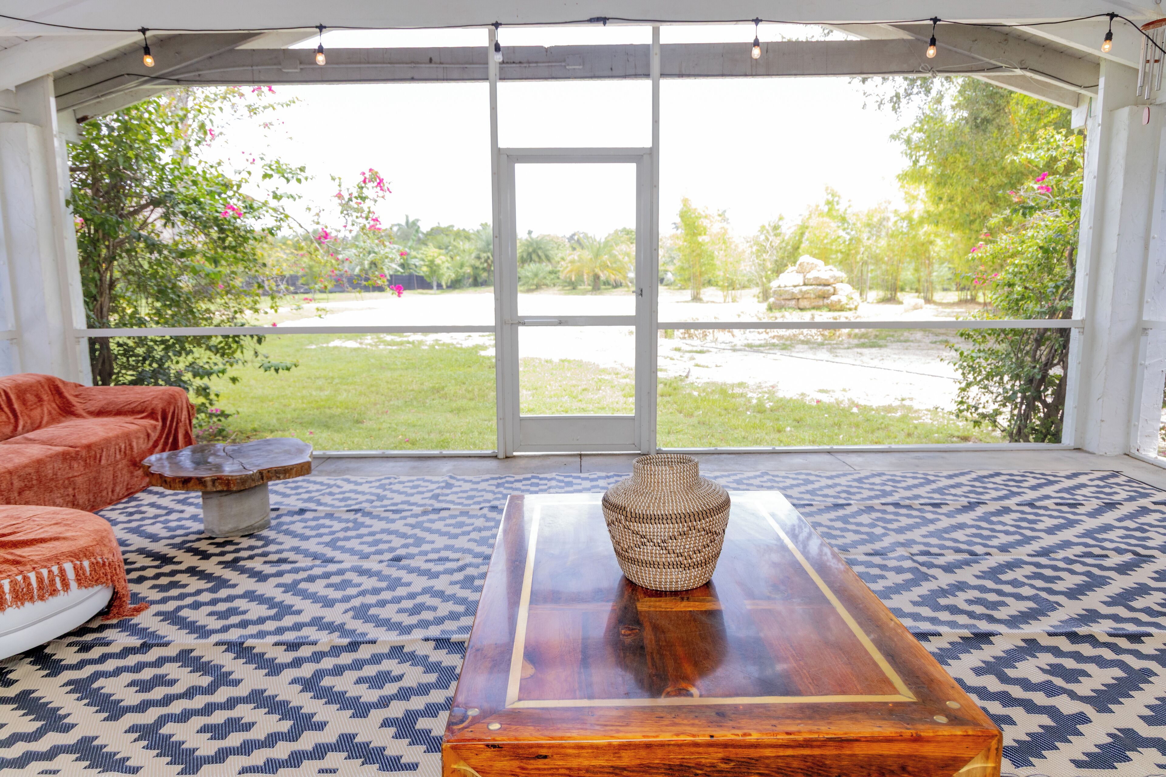 Una habitación con un ventanal grande, una mesa de madera, un tapete estampado y un sofá.