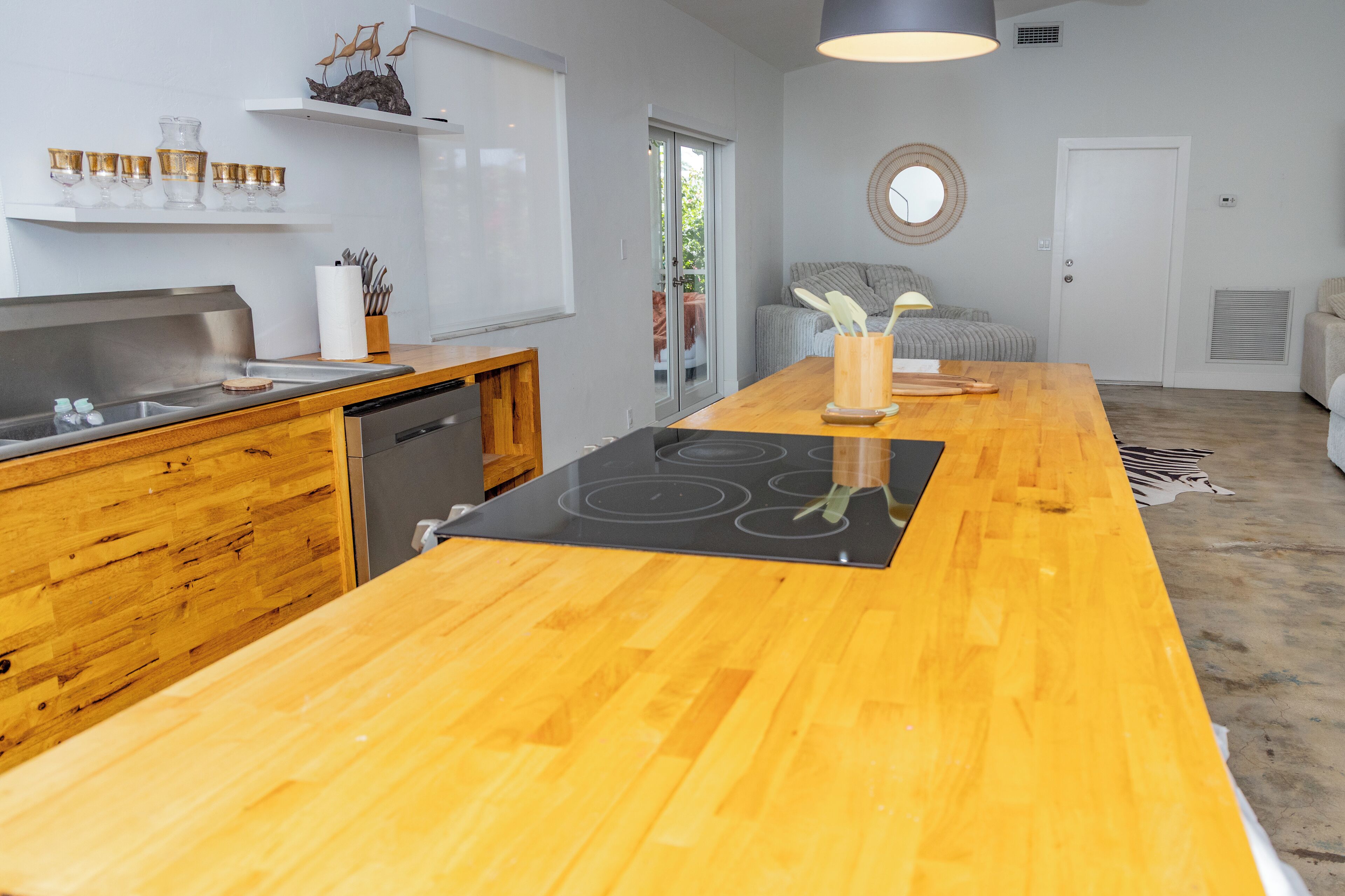 Une cuisine moderne dotée d’un plan de travail en bois, d’un lave-vaisselle encastré et d’un îlot central avec une plaque de cuisson.