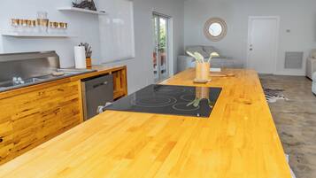 Une cuisine moderne dotée d’un plan de travail en bois, d’un lave-vaisselle encastré et d’un îlot central avec une plaque de cuisson.