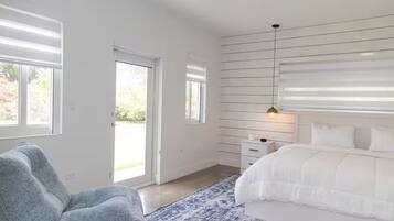 Une chambre à coucher avec un lit, une chaise, une table de chevet et une fenêtre.