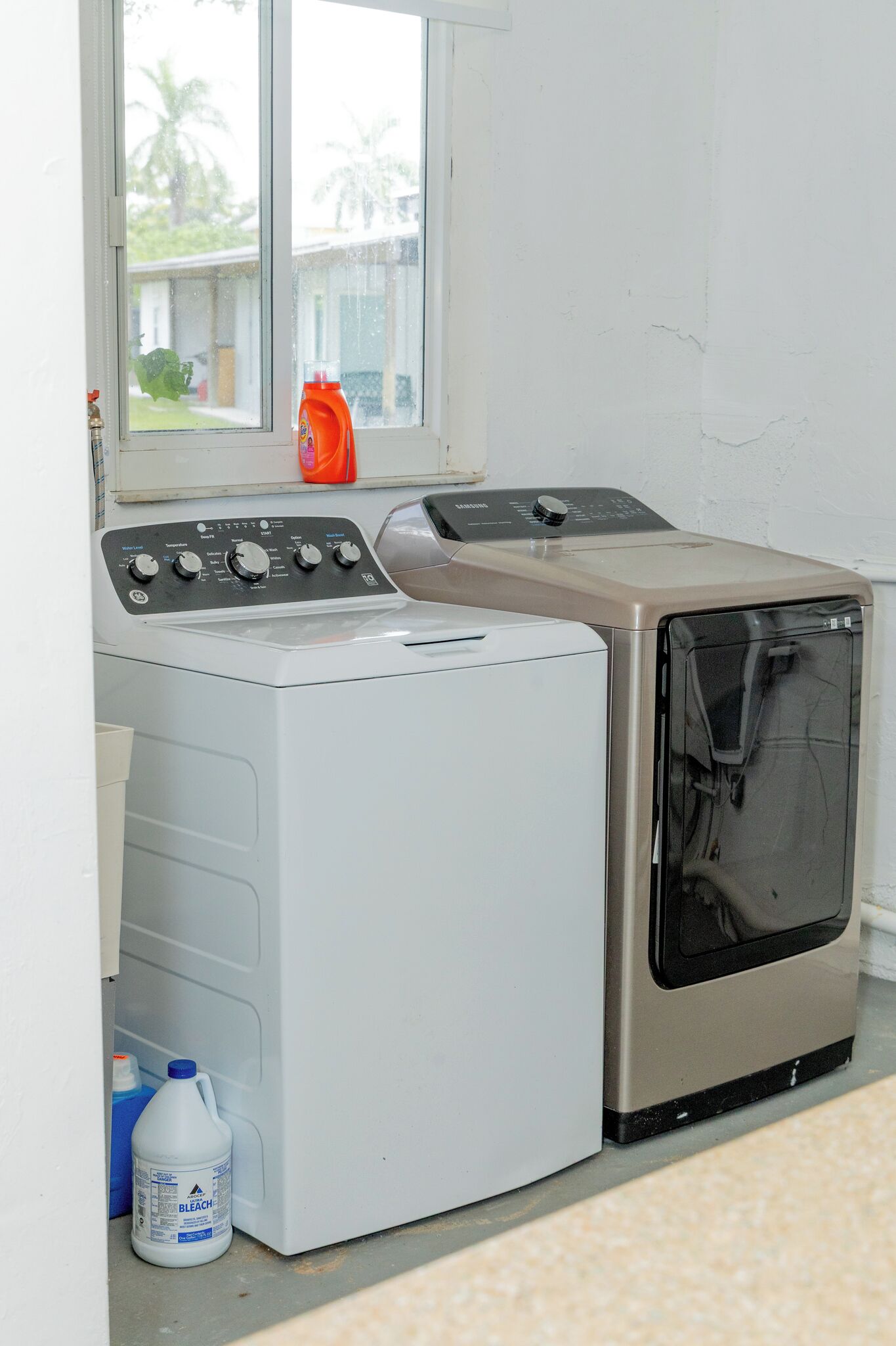 A front-loading washing machine and dryer in a laundry room with a window above.