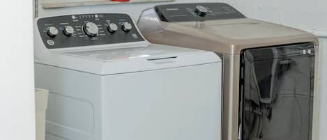 A front-loading washing machine and dryer in a laundry room with a window above.