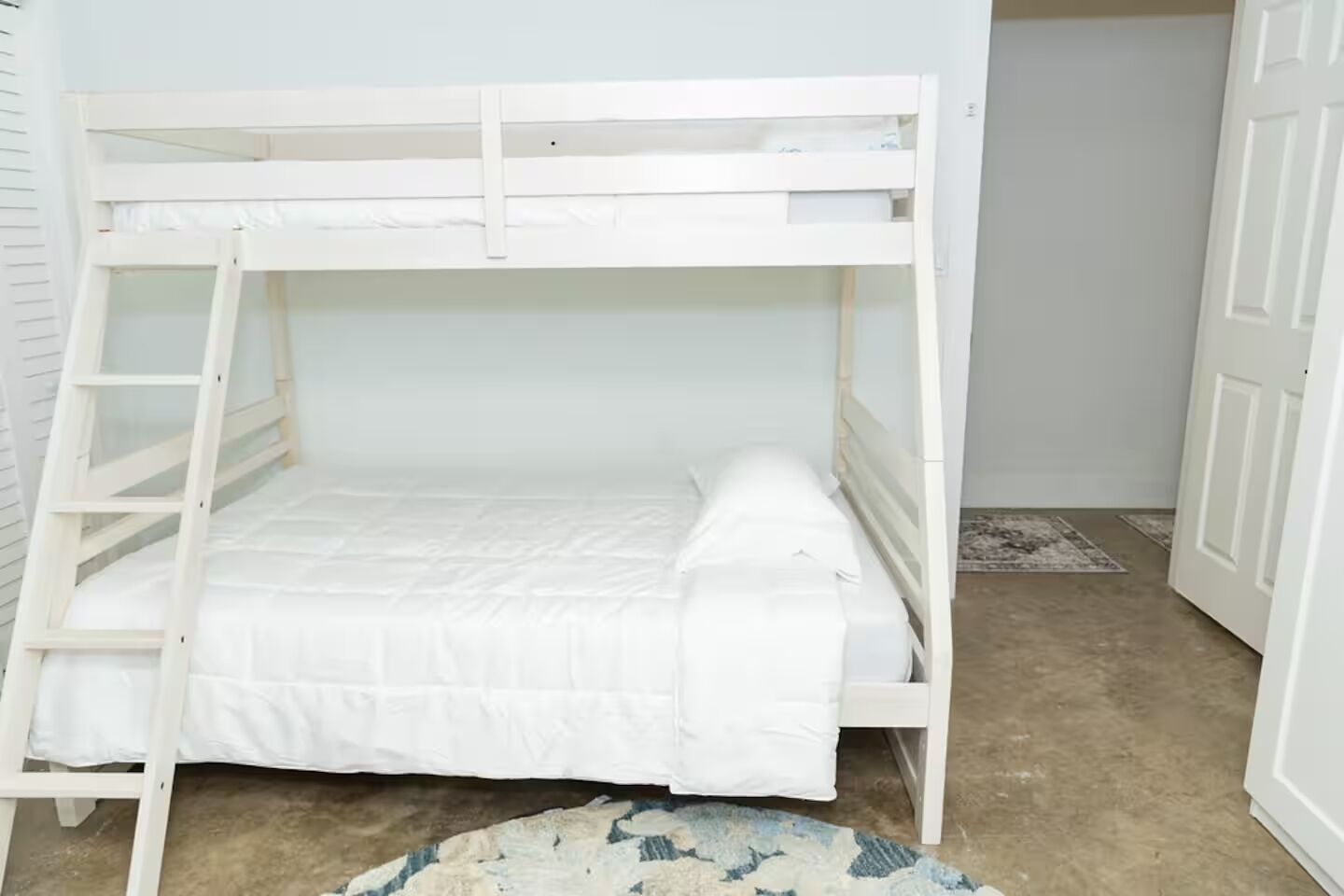 A bunk bed with a ladder, a white mattress, and a small rug on the floor.