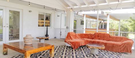 A covered outdoor seating area with a sofa, a coffee table, and a rug.