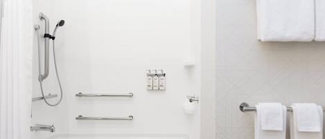 Baño con bañera, ducha, barras de apoyo y un perchero.