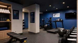 A fitness center with exercise equipment, a bench, and a wall with a sign indicating it's ready for guests. - Holiday Inn Express Troyes Gare By Ihg (Troyes)