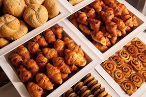 Diversos produtos de panificação, incluindo pão, croissants e cinnamon rolls.