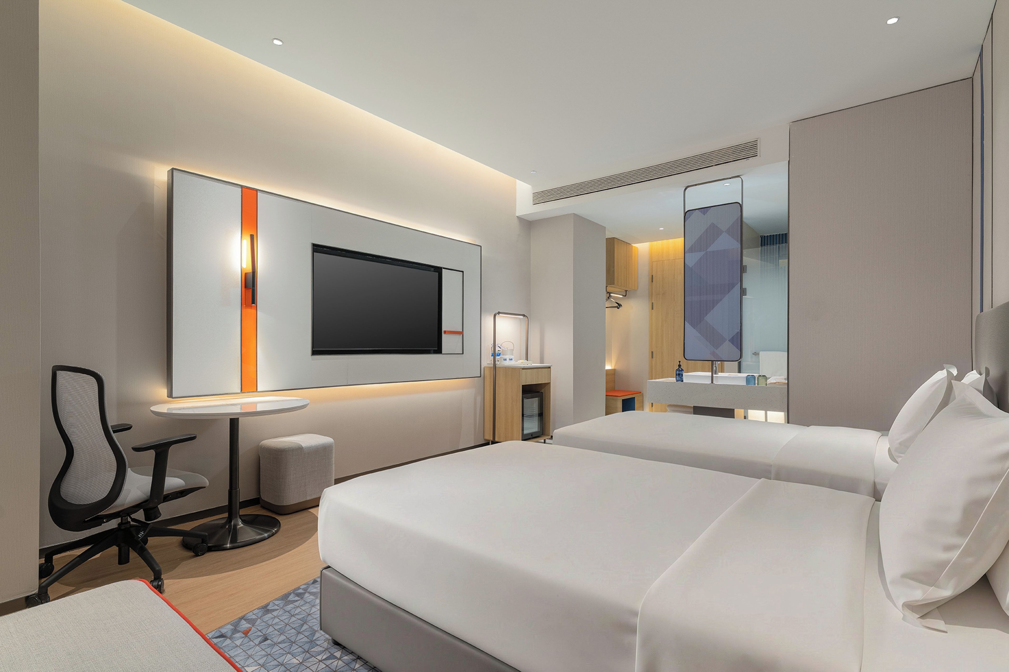 A hotel room with two beds, a desk, a chair, a TV, and a mirror.