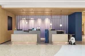A hotel reception area with two reception desks, a panda statue, and modern lighting fixtures. - Holiday Inn Express Dujiangyan Ctc By Ihg (Chengdu)