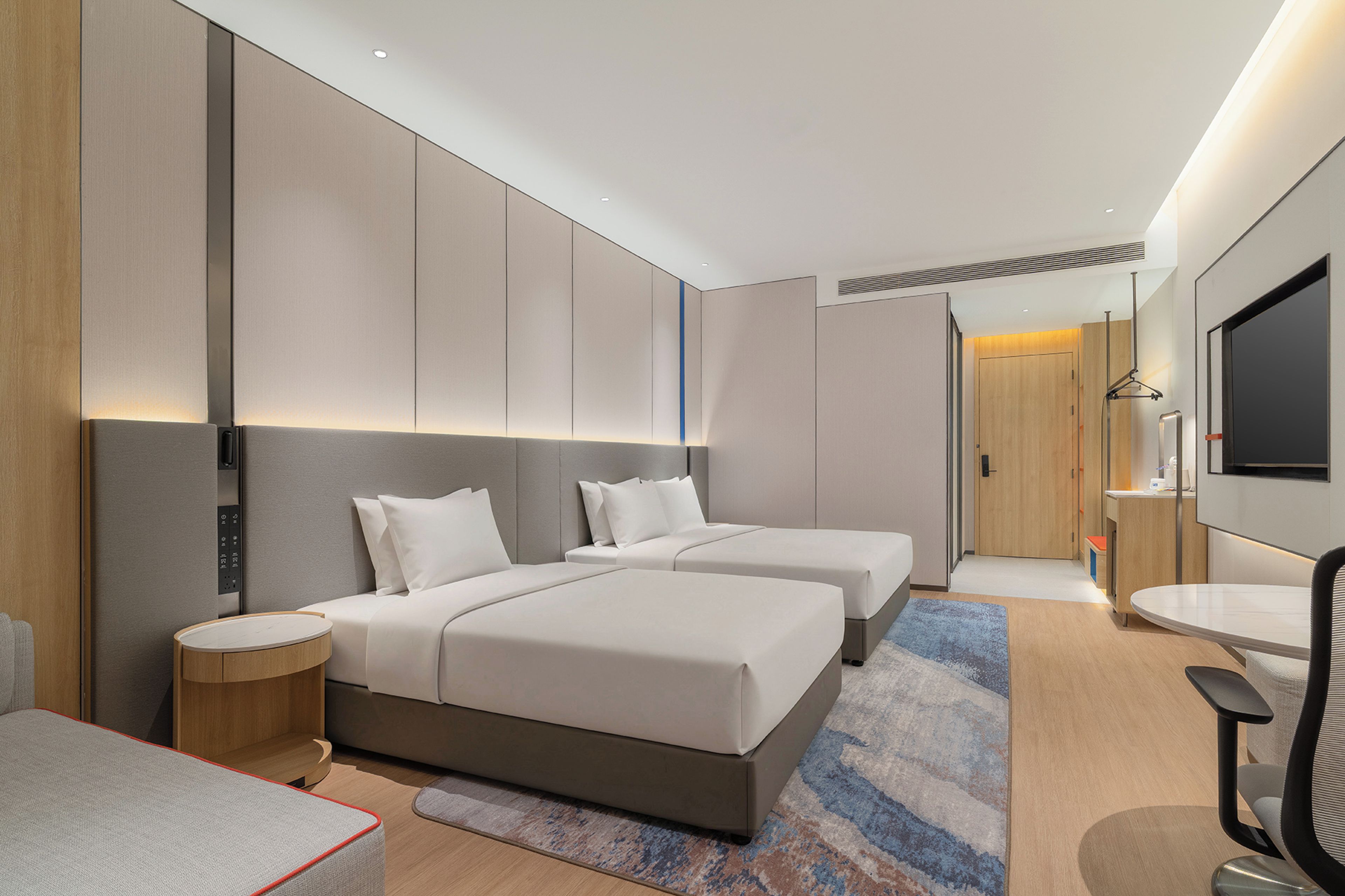 Een moderne hotelkamer met twee bedden, een nachtkastje, een bureau, een stoel en een televisie.