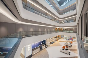 A multi-level atrium with a central open space, glass railings, and a reception area with seating. - Holiday Inn Express Dujiangyan CTC (Chengdu)