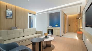Ein modernes Wohnzimmer mit einer Couch, zwei Beistelltischen und einem Couchtisch. Durch einen offenen Durchgang ist eine Küche mit Spüle und Schränken erkennbar.