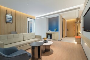 A modern living room with a sofa, two side tables, and a coffee table. There is a kitchen area with a sink and cabinets visible through an open doorway. - Holiday Inn Express Dujiangyan CTC (Chengdu)