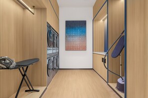 A laundry room with a wall-mounted washing machine, a drying rack, and a folding table.