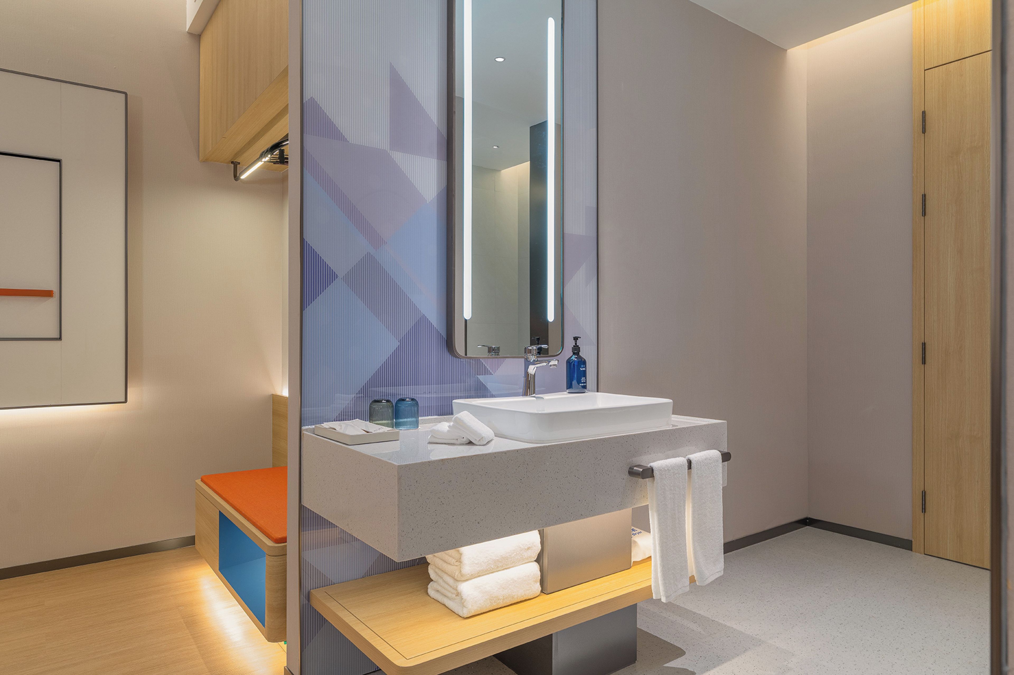 A modern bathroom with a large mirror, a sink, and a wooden bench.