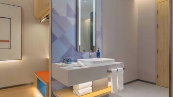 A modern bathroom with a large mirror, a sink, and a wooden bench.