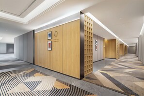 A modern hotel corridor with wooden panel walls, numbered doors, and patterned carpet flooring. - Holiday Inn Express Dujiangyan CTC (Chengdu)