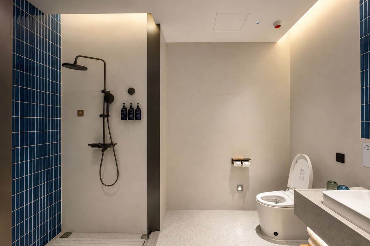 A modern bathroom with a shower, toilet, and sink.