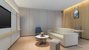 A modern, well-lit room with a sofa, a small round table, a blue chair, and a television mounted on the wall.