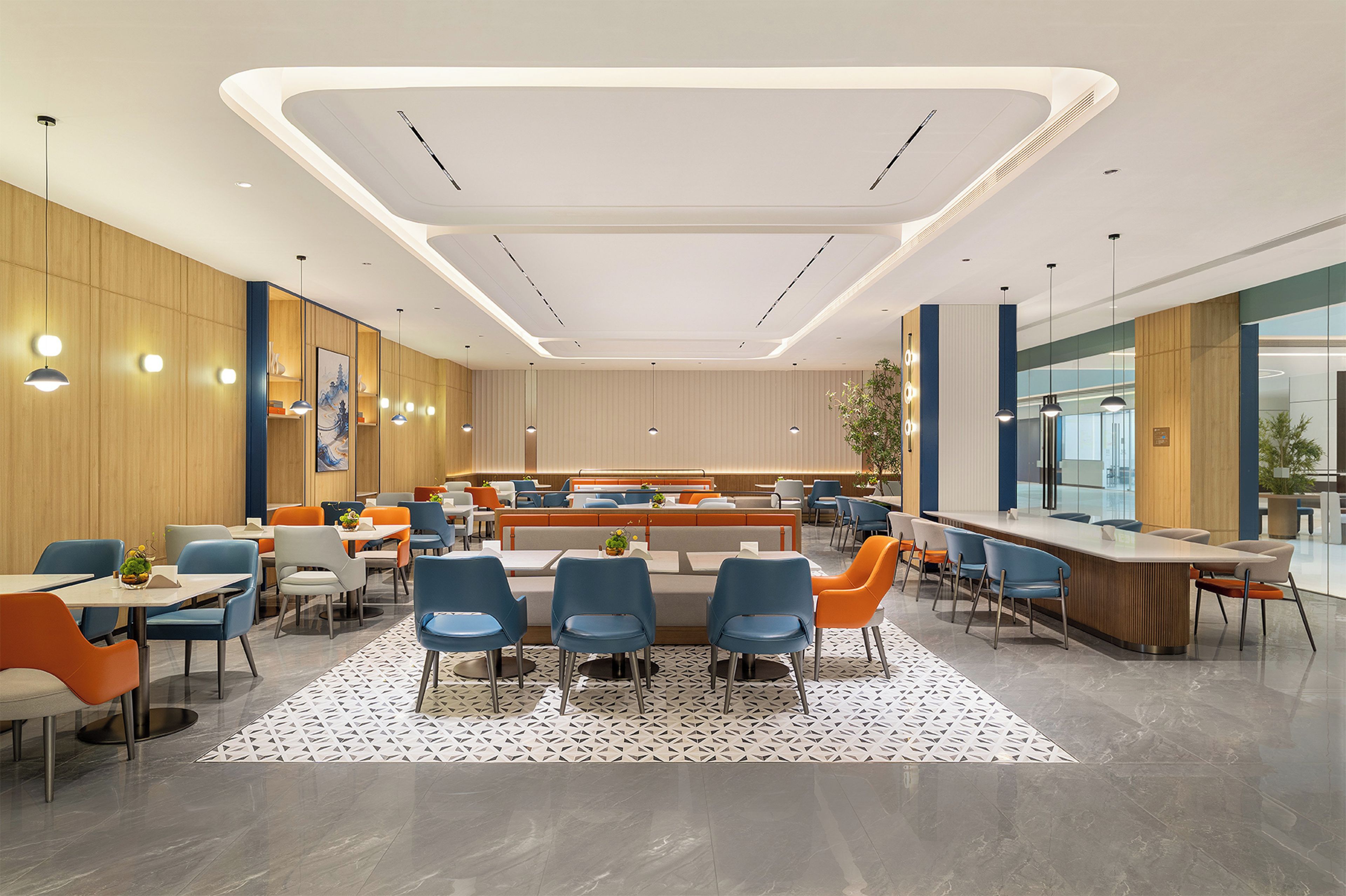 A modern dining area with high tables and chairs, a central seating area, and a large window providing a view of the outdoors.