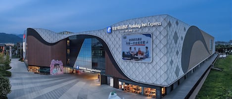 A Holiday Inn Express hotel with a modern architectural design, featuring a prominent curved facade and a large billboard advertising the hotel.
