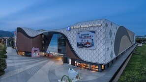 A Holiday Inn Express hotel with a modern architectural design, featuring a prominent curved facade and a large billboard advertising the hotel. - Holiday Inn Express Dujiangyan CTC (Chengdu)