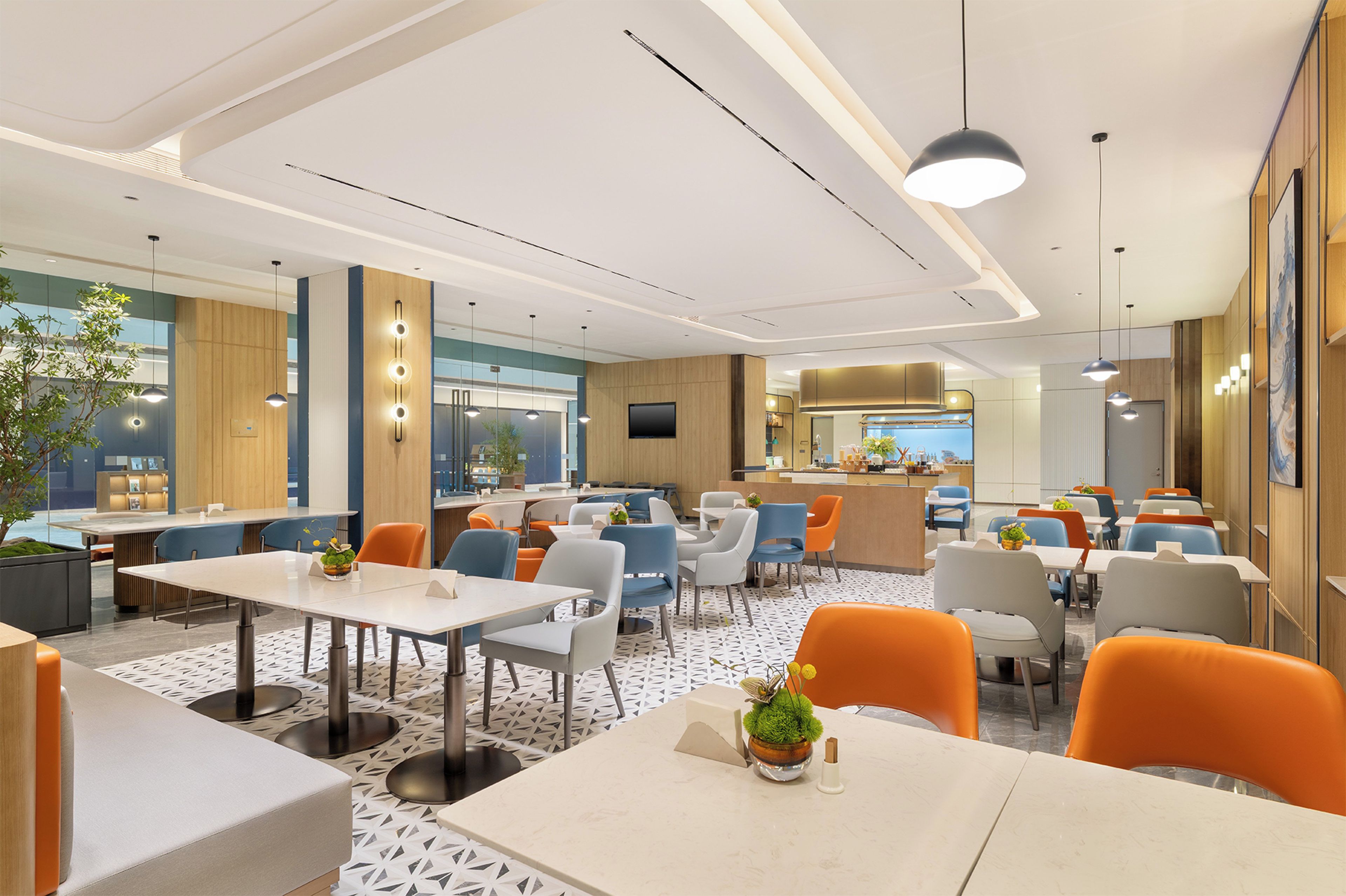 A modern restaurant with multiple dining tables and chairs, a bar area, and a kitchen in the background.