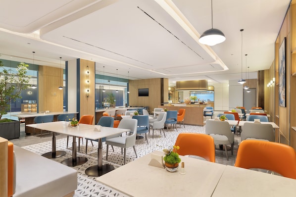 Un restaurante moderno con varias mesas y sillas, una zona de bar y una cocina al fondo.