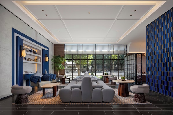 A modern lobby with a central seating area, large windows, and a patterned wall. - Holiday Inn Express Danyang By Ihg (Zhenjiang)