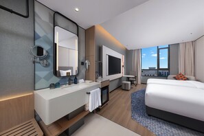 A modern hotel room with a large bed, a TV, a bathroom with a mirror, and a view of the city. - Holiday Inn Express Danyang By Ihg (Zhenjiang)