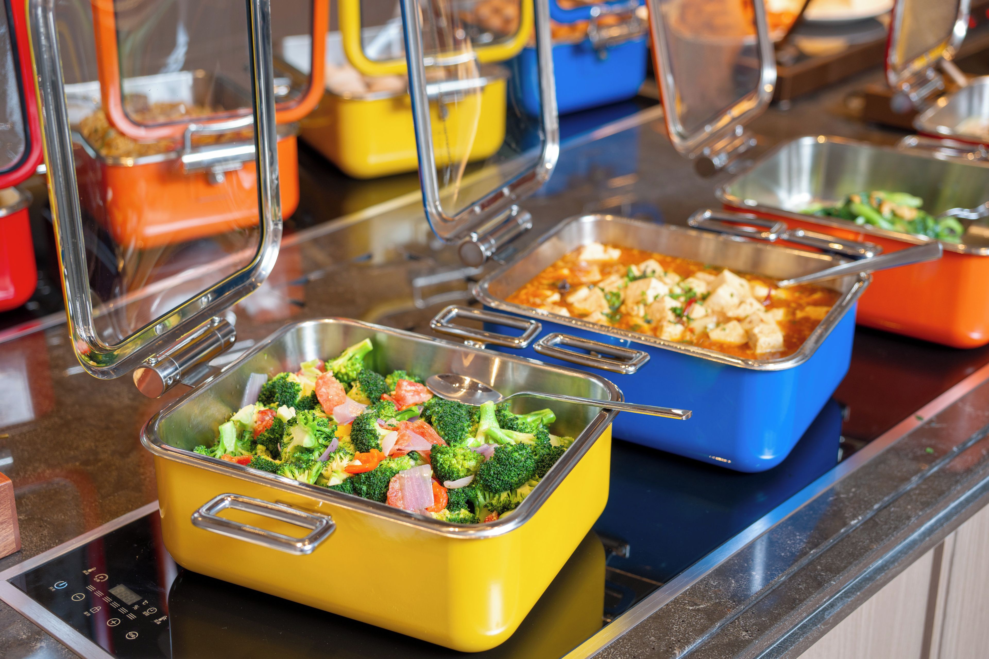 Buffet-style food service with various dishes in metal serving containers.