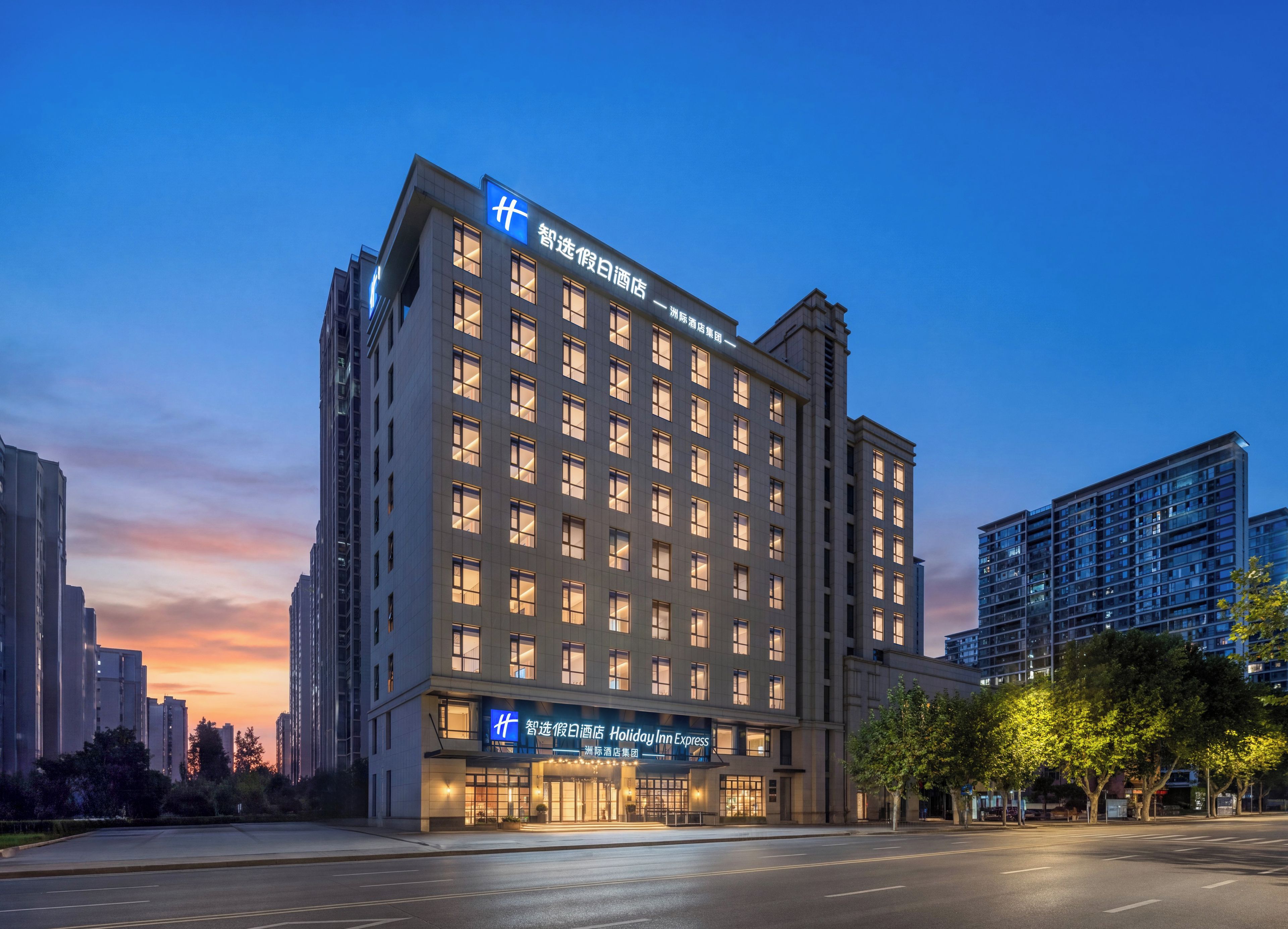 A multi-story hotel with a prominent sign, large windows, and a well-lit facade.