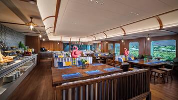 A restaurant with a central bar area, seating arrangements, and a view of the outdoors.