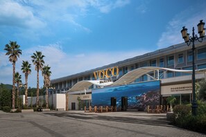 A modern building with a large sign reading 'VOCO' and a scenic mural of a beach and mountains. - Voco Anji Treasure Island Park By Ihg (Huzhou)