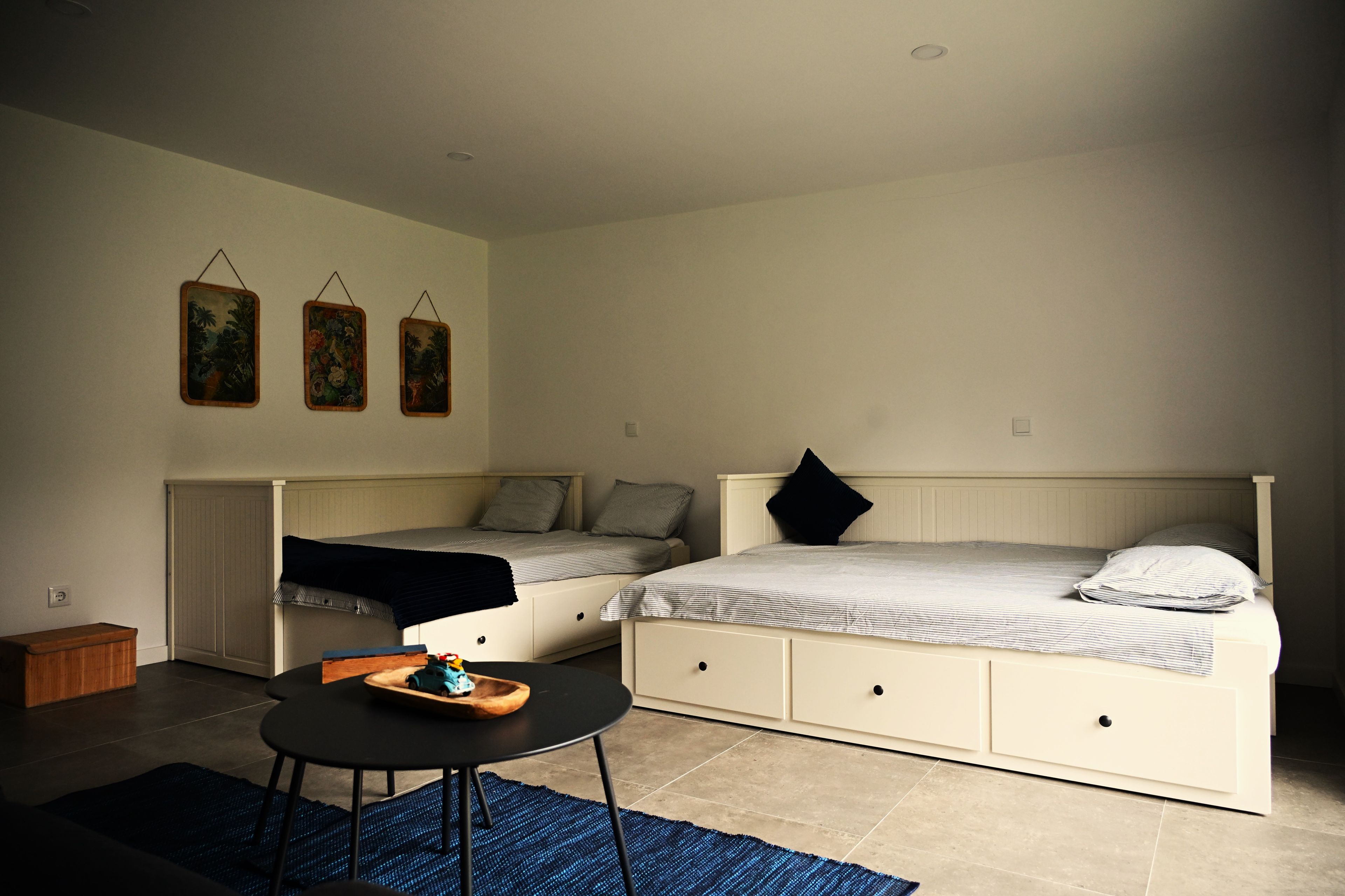 Un dormitorio con dos camas, una mesita y una alfombra azul.