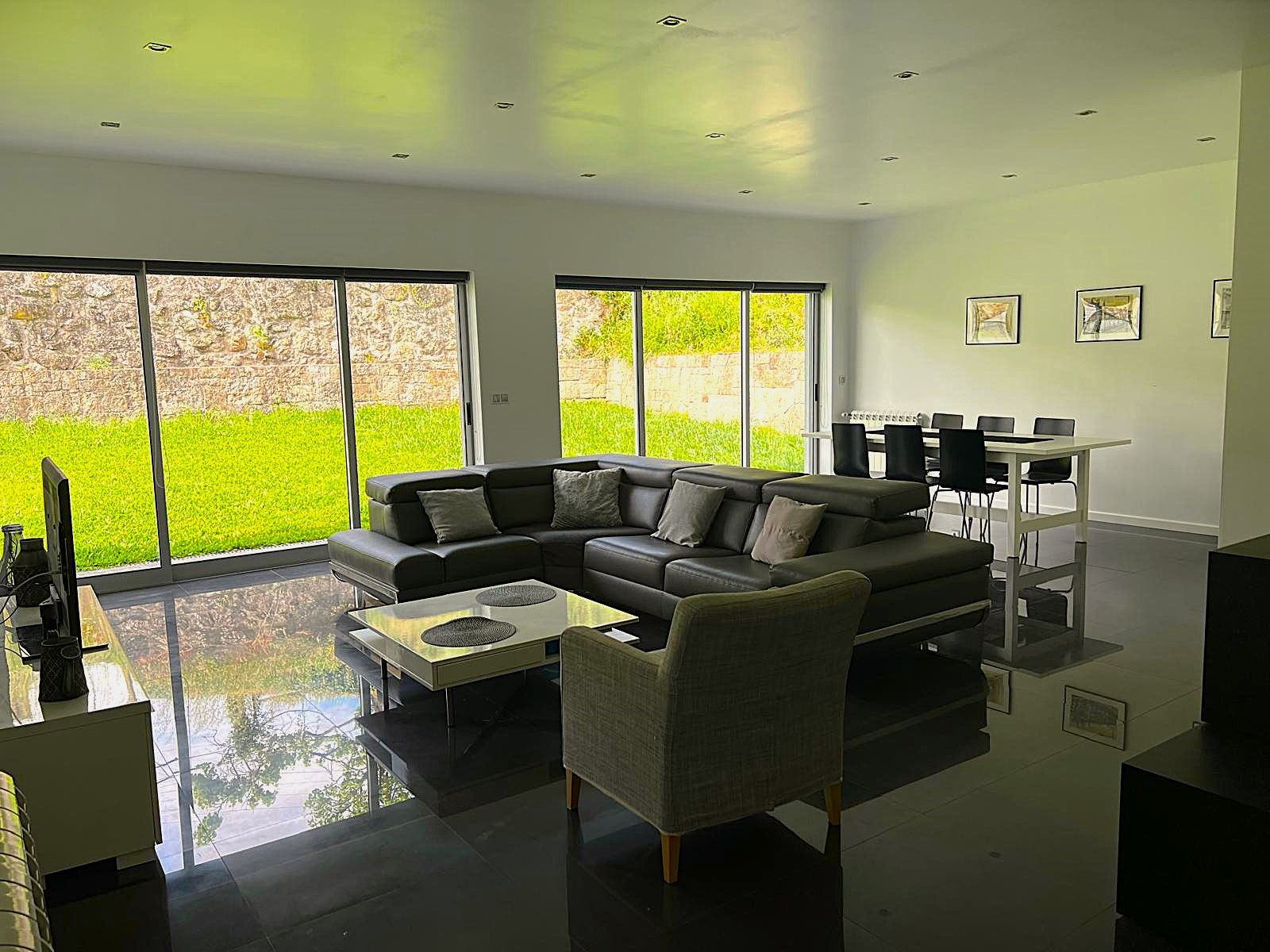 Uma sala de estar moderna com sofá seccional, mesa de centro e área de jantar com cadeiras.