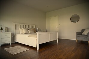 Ein Schlafzimmer mit einem Bett, einem Nachttisch, einem Stuhl und einer Tür.