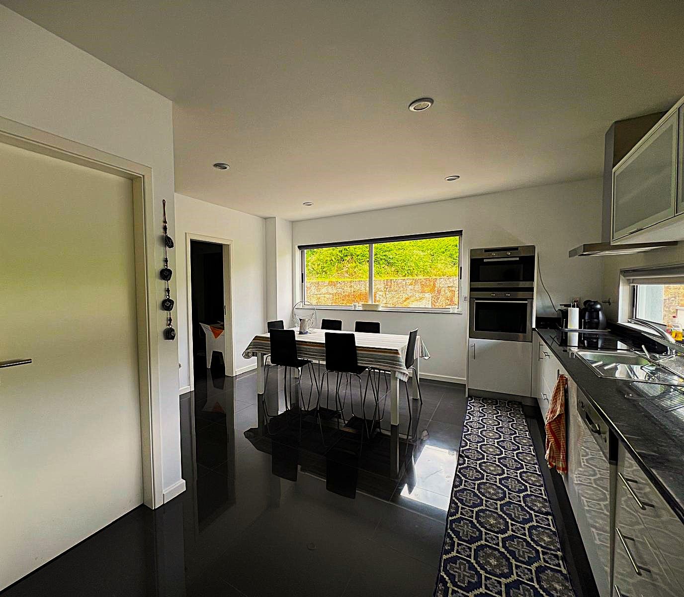 A modern kitchen with a dining area, a large window, and a patterned floor.