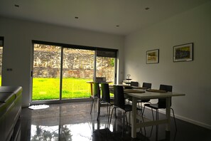 A modern dining area with a glass door leading to a garden.