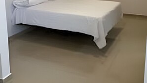 A single-bed room with a ceiling fan, recessed lighting, and a white wall.