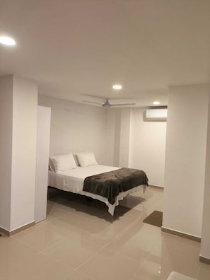 Ein Schlafzimmer mit Bett, Deckenventilator, eingelassener Beleuchtung und Klimaanlage.