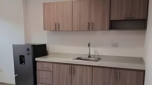 A modern kitchen with wooden cabinets, a black refrigerator, and a sink.