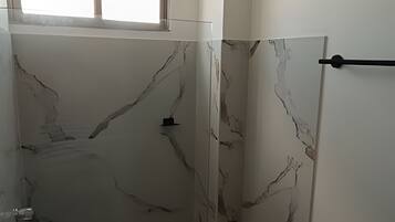 Un baño con pared de mármol y un perchero negro.
